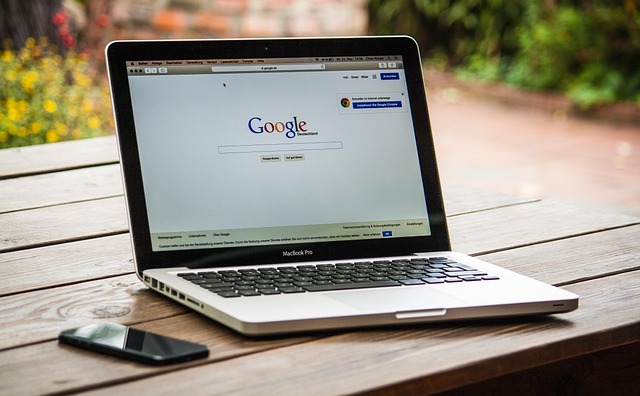 A laptop showing the Google homepage on a wooden table