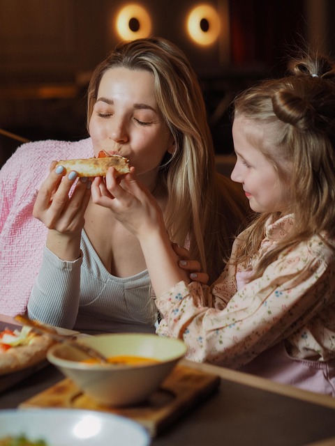 A parent and child sharing pizza at a restaurant table